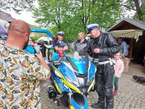 Policjant prezentujący motocykl służbowy zainteresowanym dzieciom.