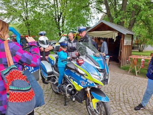 Policjant prezentujący motocykl służbowy zainteresowanym dzieciom.