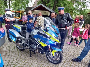 Policjant prezentujący motocykl służbowy zainteresowanym dzieciom.