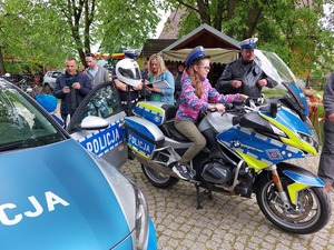 Policjant prezentujący motocykl służbowy zainteresowanym dzieciom.