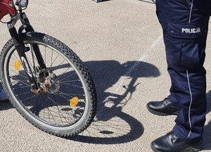 Na zdjęciu umundurowany policjant kontrolujący rowerzystę.