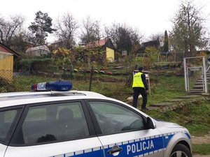 Umundurowany policjant wchodzący na schody, idący w kierunku działek rekreacyjnych.