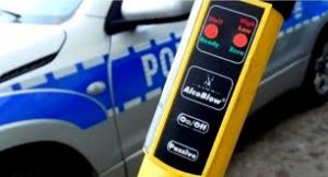 Urządzenie do badania stanu trzeźwości. W tle oznakowany radiowóz.