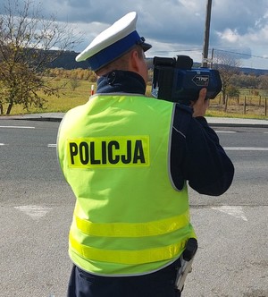 Umundurowany policjant używający miernika prędkości.