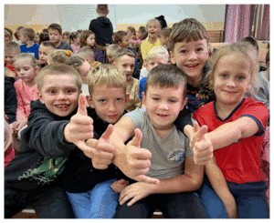 Umundurowani policjanci rozmawiają z grupą dzieci o bezpieczeństwie.