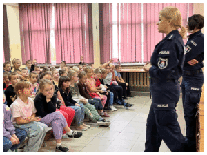 Umundurowani policjanci rozmawiają z grupą dzieci o bezpieczeństwie.