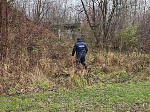 Umundurowany policjant kontrolujący tereny pustostanów w poszukiwaniu osób bezdomnych, potrzebujących pomocy.