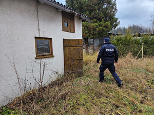 Umundurowany policjant kontrolujący tereny pustostanów w poszukiwaniu osób bezdomnych, potrzebujących pomocy.