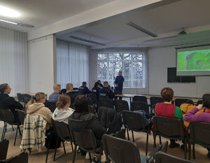 Policjanci prowadzący debatę społeczną na temat bezpieczeństwa młodzieży. Na zdjęciu widać prelegentów oraz uczestników.