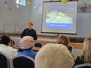 Policjanci przeprowadzający debatę społeczną poświęconą bezpieczeństwu seniorów. Na zdjęciu widać prelegentów oraz uczestników debaty siedzących na krzesłach.