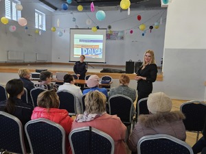 Policjanci przeprowadzający debatę społeczną poświęconą bezpieczeństwu seniorów. Na zdjęciu widać prelegentów oraz uczestników debaty siedzących na krzesłach.