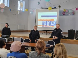 Policjanci przeprowadzający debatę społeczną poświęconą bezpieczeństwu seniorów. Na zdjęciu widać prelegentów oraz uczestników debaty siedzących na krzesłach.