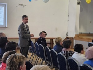 Policjanci przeprowadzający debatę społeczną poświęconą bezpieczeństwu seniorów. Na zdjęciu widać prelegentów oraz uczestników debaty siedzących na krzesłach.