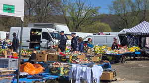 Policjanci patrolujący targowisko. W tle widać sprzedawców i kupujących oraz towar, którym handlują.