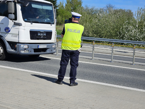 Umundurowani policjanci kontrolujący pojazdy na drodze.