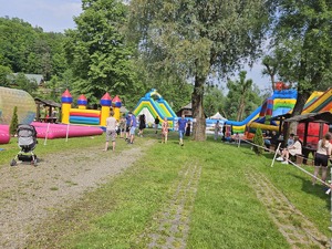 Zdjęcia zrobione podczas pikniku. Na fotografiach widać atrakcje, zjeżdżalnie, trampoliny oraz inne zabawy dla najmłodszych. Widać również uczestników pikniku.