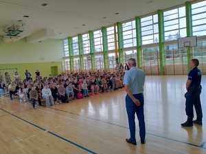 Policjant przeprowadzający pogadankę z dziećmi na temat bezpieczeństwa .