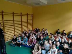 Policjant przeprowadzający pogadankę z dziećmi na temat bezpieczeństwa .