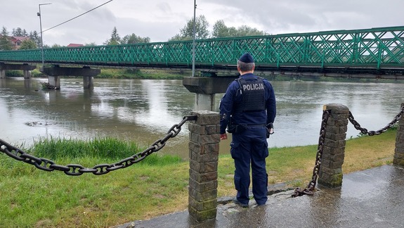 Umundurowany policjant patrolujący brzeg rzeki San.