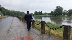 Umundurowany policjant patrolujący brzeg rzeki San.