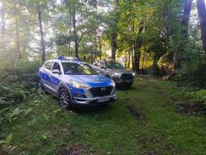 Czynności wykonywane prze policjantów wspólnie ze strażnikami leśnymi. Radiowóz zaparkowany w lesie.