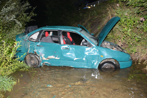 Niebieski samochód z widocznymi uszkodzeniami, znajdujący się w rzece.