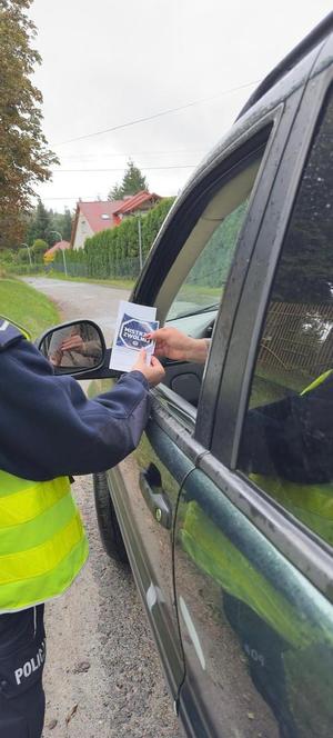 Policjant kontrolujący stan trzeźwości kierujących. Podczas działań wykorzystywany jest również miernik prędkości.