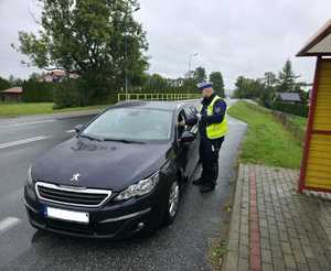 Policjant kontrolujący stan trzeźwości kierujących. Podczas działań wykorzystywany jest również miernik prędkości.