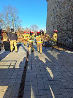 Współdziałanie służb w związku z ćwiczeniami, które odbywały się na terenie Zamku Królewskiego w Sanoku. Widać samochody straży pożarnej, policji, pogotowia ratunkowego oraz funkcjonariuszy realizujących zadania własne oraz wspólne.
