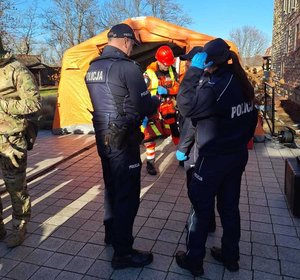 Współdziałanie służb w związku z ćwiczeniami, które odbywały się na terenie Zamku Królewskiego w Sanoku. Widać samochody straży pożarnej, policji, pogotowia ratunkowego oraz funkcjonariuszy realizujących zadania własne oraz wspólne.