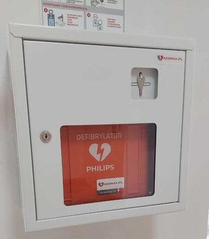 Zdjęcie defibrylatora AED, który jest zamocowany do ściany w poczekalni Komendy Powiatowej Policji w Sanoku.