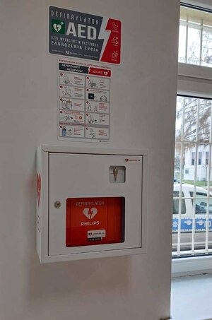 Zdjęcie defibrylatora AED, który jest zamocowany do ściany w poczekalni Komendy Powiatowej Policji w Sanoku.
