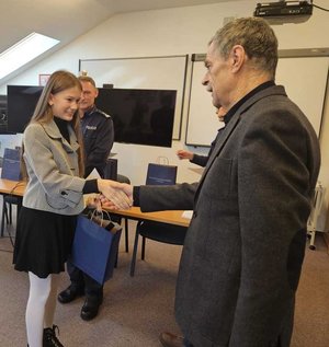 Rozstrzygnięcie konkursu pt. "Bezpieczne Wakacje 2025". Na zdjęciu widać osoby, które oceniały prace uczestników, osoby wręczające nagrody oraz nagrodzone dzieci razem z opiekunami.