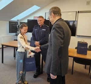 Rozstrzygnięcie konkursu pt. "Bezpieczne Wakacje 2025". Na zdjęciu widać osoby, które oceniały prace uczestników, osoby wręczające nagrody oraz nagrodzone dzieci razem z opiekunami.