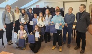 Rozstrzygnięcie konkursu pt. "Bezpieczne Wakacje 2025". Na zdjęciu widać osoby, które oceniały prace uczestników, osoby wręczające nagrody oraz nagrodzone dzieci razem z opiekunami.