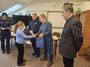 Rozstrzygnięcie konkursu pt. "Bezpieczne Wakacje 2025". Na zdjęciu widać osoby, które oceniały prace uczestników, osoby wręczające nagrody oraz nagrodzone dzieci razem z opiekunami.