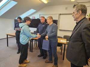 Rozstrzygnięcie konkursu pt. "Bezpieczne Wakacje 2025". Na zdjęciu widać osoby, które oceniały prace uczestników, osoby wręczające nagrody oraz nagrodzone dzieci razem z opiekunami.