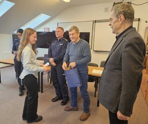 Rozstrzygnięcie konkursu pt. "Bezpieczne Wakacje 2025". Na zdjęciu widać osoby, które oceniały prace uczestników, osoby wręczające nagrody oraz nagrodzone dzieci razem z opiekunami.