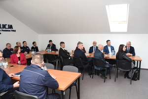 Policjanci biorący udział w naradzie rocznej w Komendzie Powiatowej Policji w Sanoku. Osoby rozmawiają na temat bezpieczeństwa w powiecie sanockim.