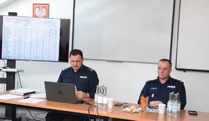 Policjanci biorący udział w naradzie rocznej w Komendzie Powiatowej Policji w Sanoku. Osoby rozmawiają na temat bezpieczeństwa w powiecie sanockim.