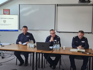 Policjanci biorący udział w naradzie rocznej w Komendzie Powiatowej Policji w Sanoku. Osoby rozmawiają na temat bezpieczeństwa w powiecie sanockim.