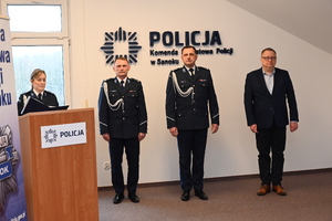 Uroczystość z okazji przejścia na emeryturę dwóch sanockich policjantów. Kadra kierownicza żegna kolegów wręczając im kwiaty i pamiątkowe prezenty.