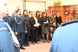 Uroczystość z okazji przejścia na emeryturę dwóch sanockich policjantów. Kadra kierownicza żegna kolegów wręczając im kwiaty i pamiątkowe prezenty.