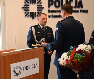 Uroczystość z okazji przejścia na emeryturę dwóch sanockich policjantów. Kadra kierownicza żegna kolegów wręczając im kwiaty i pamiątkowe prezenty.
