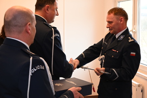 Uroczystość z okazji przejścia na emeryturę dwóch sanockich policjantów. Kadra kierownicza żegna kolegów wręczając im kwiaty i pamiątkowe prezenty.