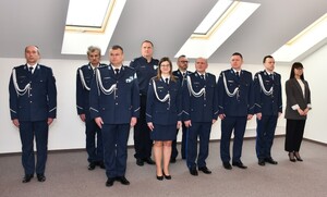 Na zdjęciu widać umundurowanych policjantów stojących w dwuszeregu. Policjanci znajdują się w pomieszczeniu. W tle białe ściany oraz okna połaciowe.