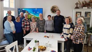 Na zdjęciu dwóch umundurowanych policjantów razem z członkami klubu seniora. Zdjęcie zrobione w pomieszczeniu.