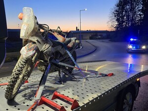 Zatrzymany motocykl na lawecie. W tle radiowóz policyjny.